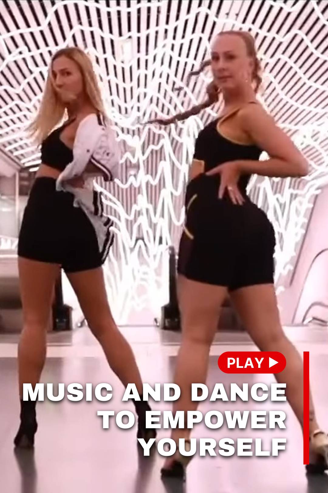 Two women in black clothes dance on stage and look back facing forward